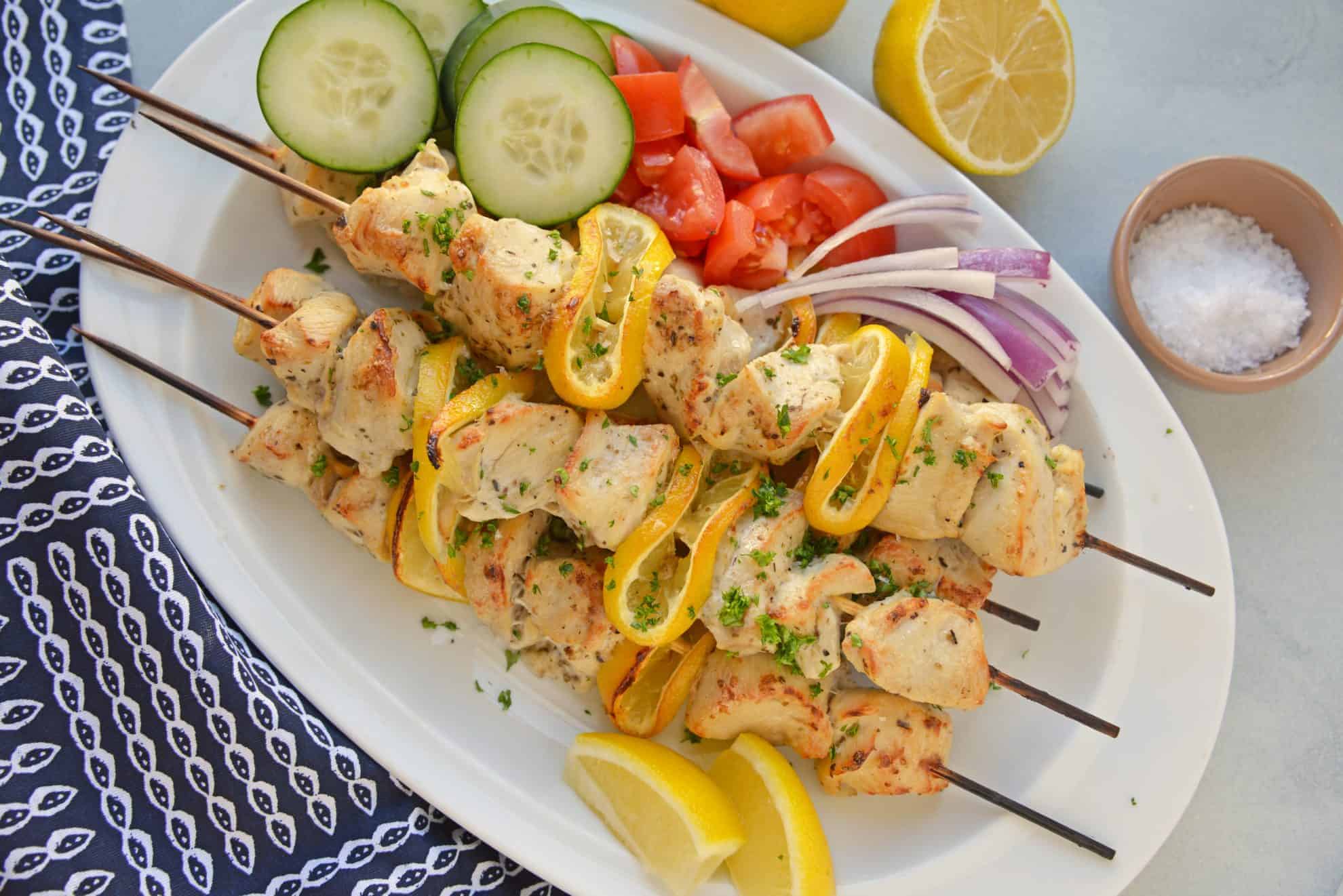 Overhead of Greek chicken kabobs with cucumber, tomato and red onion