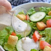 creamy salad dressing pouring onto salad