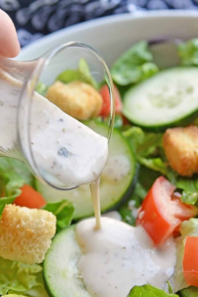 creamy salad dressing pouring onto salad