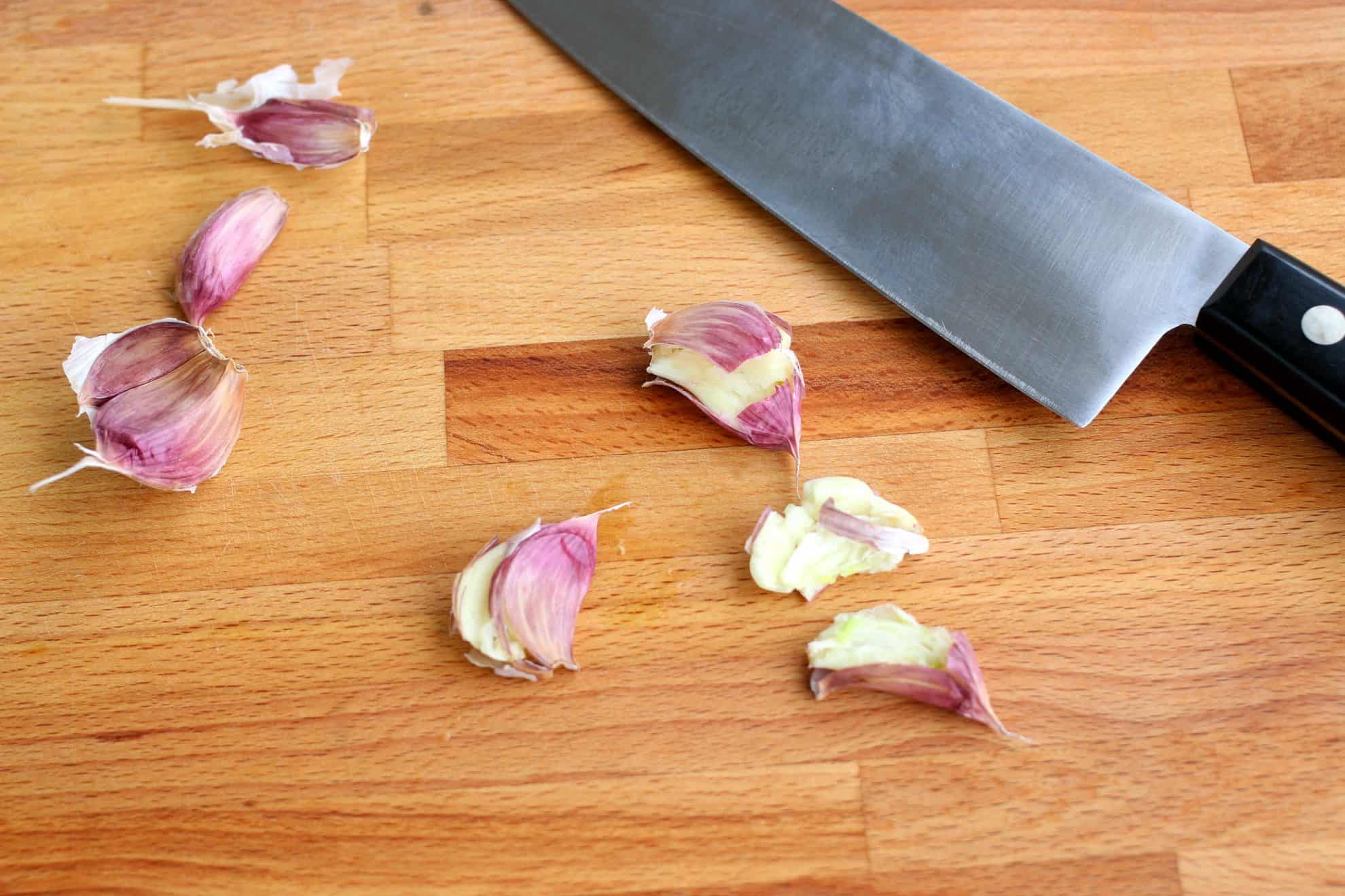 Smashed garlic on a cutting board.