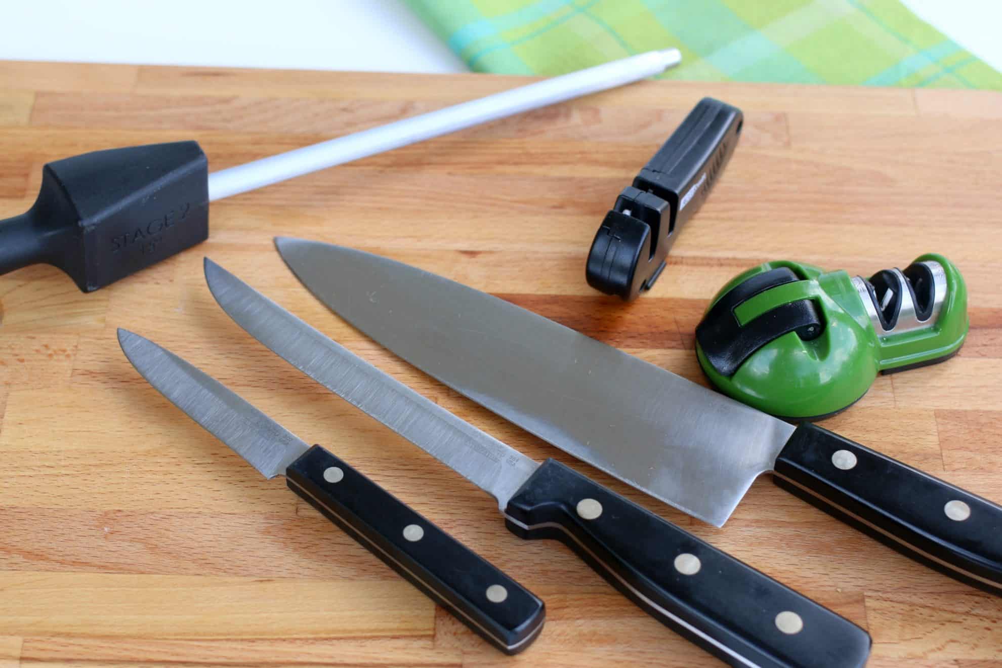 There are many tools for sharpening kitchen knifes. Some are shown here on a cutting board alongside knives.