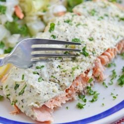 Fork cutting into pesto salmon