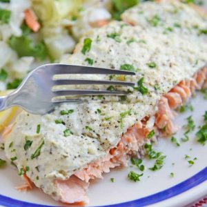 Fork cutting into pesto salmon