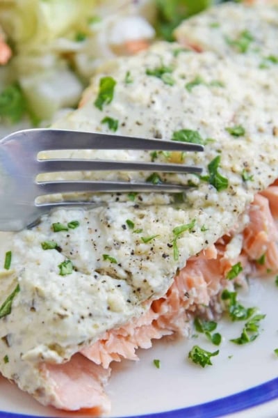 Fork cutting into pesto salmon