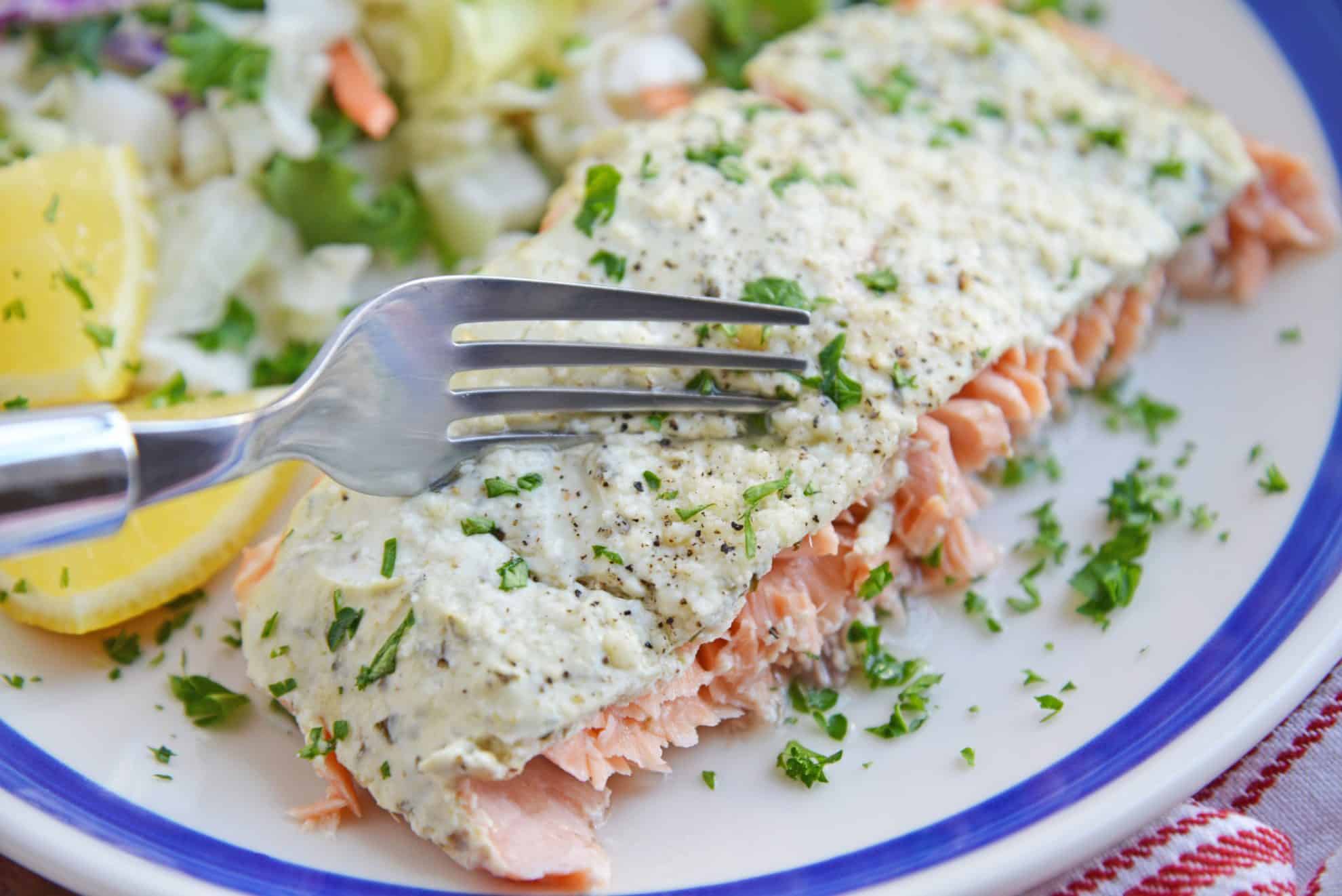 Fork cutting into pesto salmon