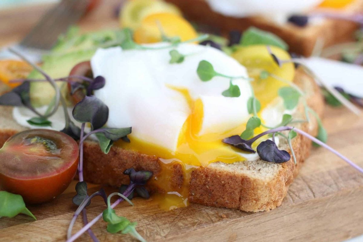 Closeup of a poached egg on avocado toast garnished with micro greens