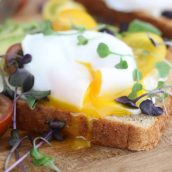 Closeup of a poached egg on avocado toast garnished with micro greens