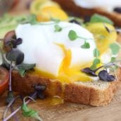 Closeup of a poached egg on avocado toast garnished with micro greens