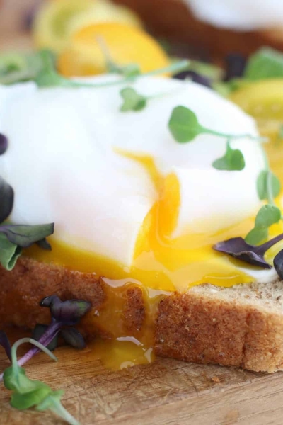 Closeup of a poached egg on avocado toast garnished with micro greens