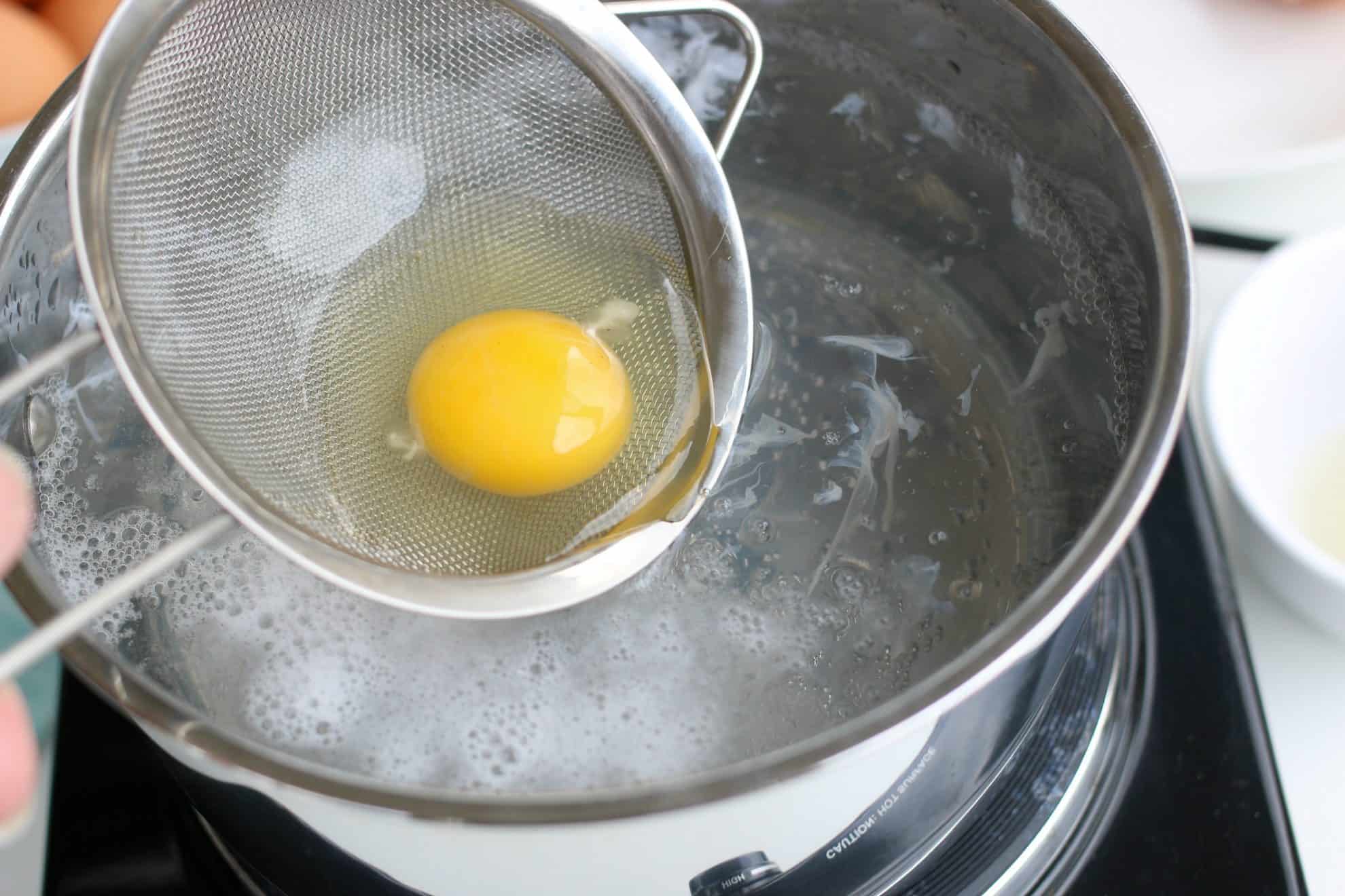 Adding an egg to simmering water to make poached eggs