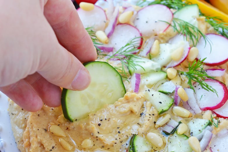 Cucumber dipping into hummus