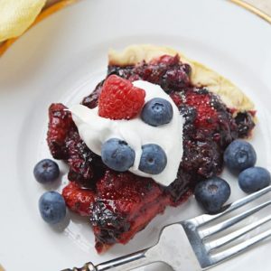 slice of mixed berry pie with whipped cream and cresh berries