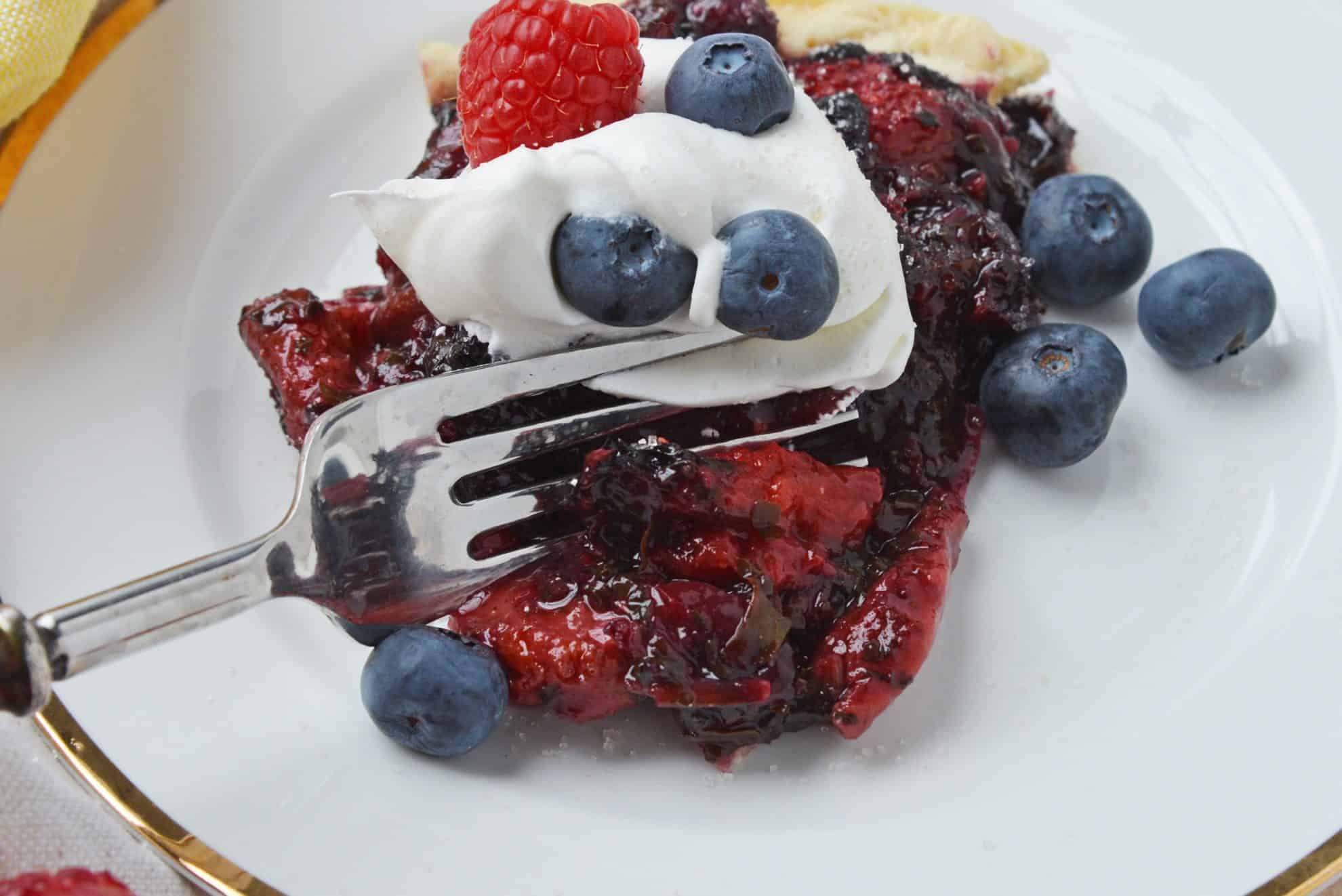 fork cutting into mixed berry pie 