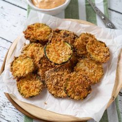 Air fryer zucchini chips on a plate with sauce