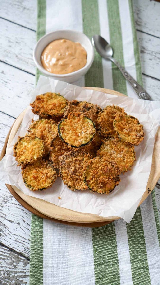 Air fryer zucchini chips on a plate with dipping sauce