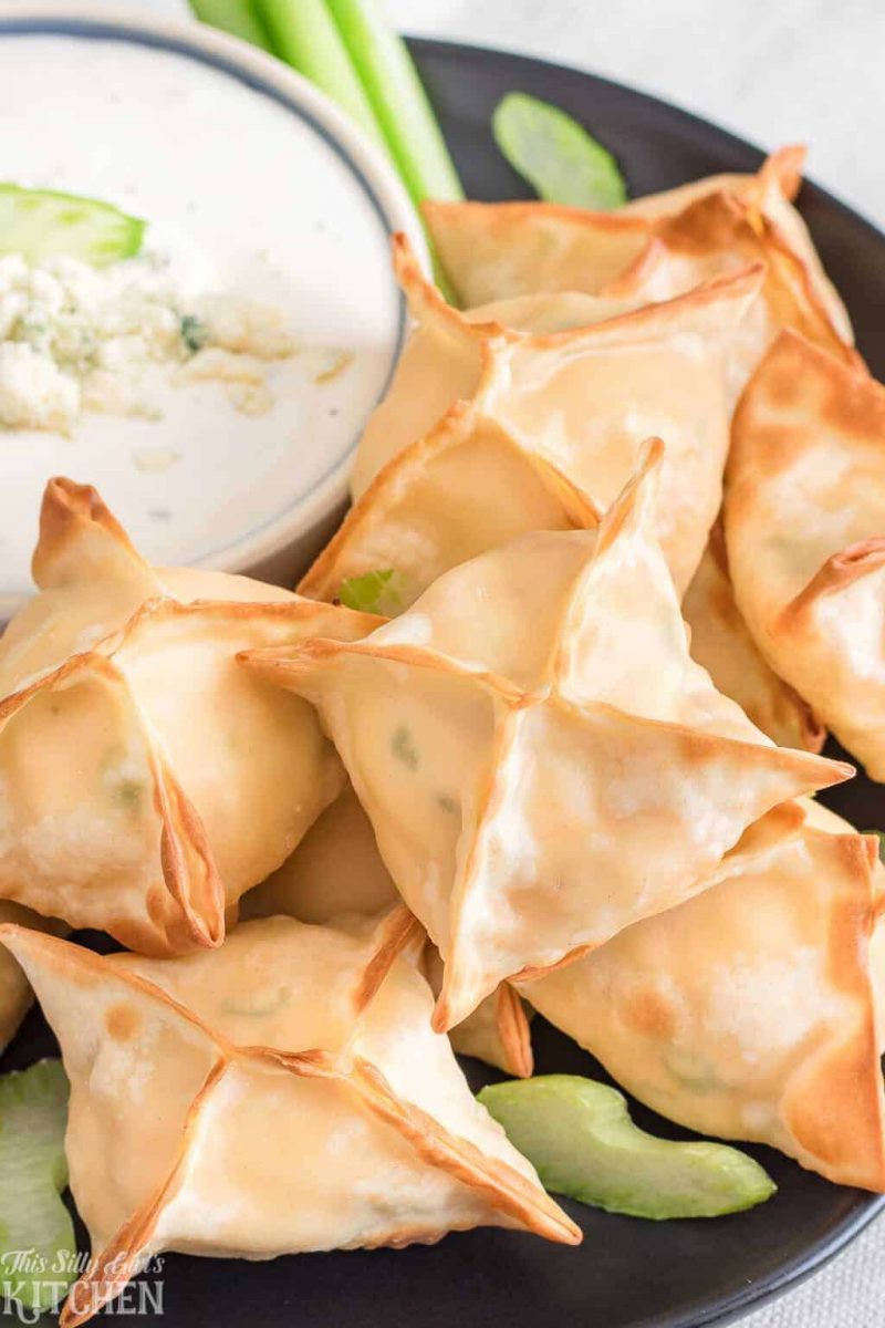 Air fryer buffalo chicken wontons on a plate with celery and sauce