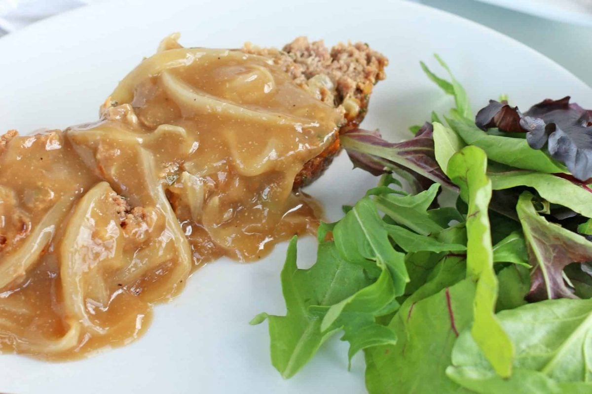 Slice of french onion meatloaf with onion gravy and a green salad 