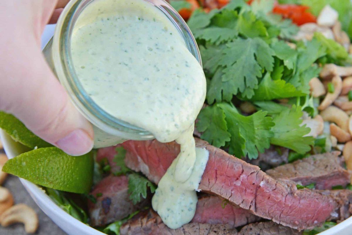 Green curry sauce pouring over steak salad 