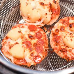 three mini pizzas in an air fryer