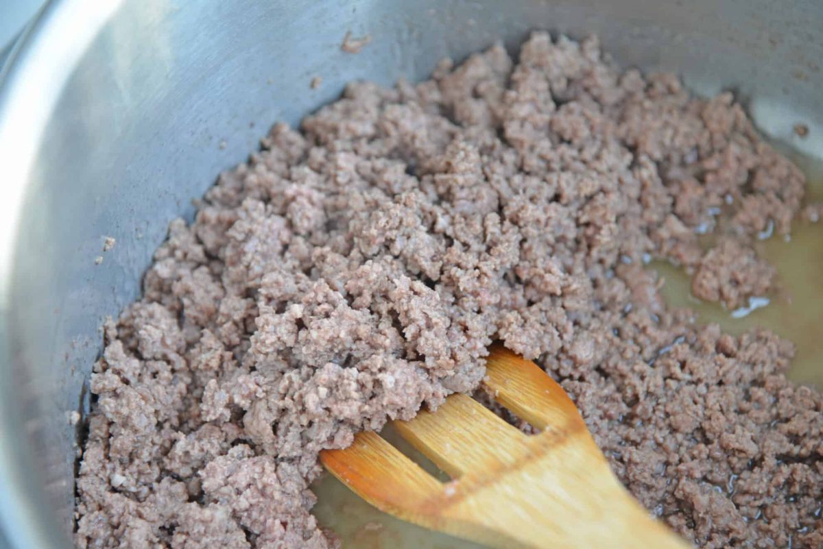 angled shot of wooden spoon in pan of ground beef