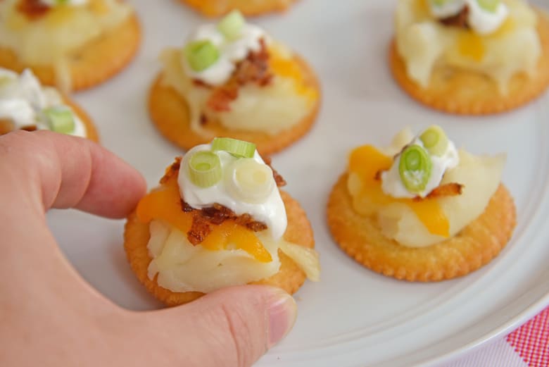 Hand reaching for a loaded baked potato cracker 