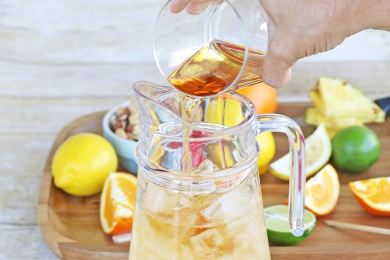 Rum pouring into a pitcher of rum punch