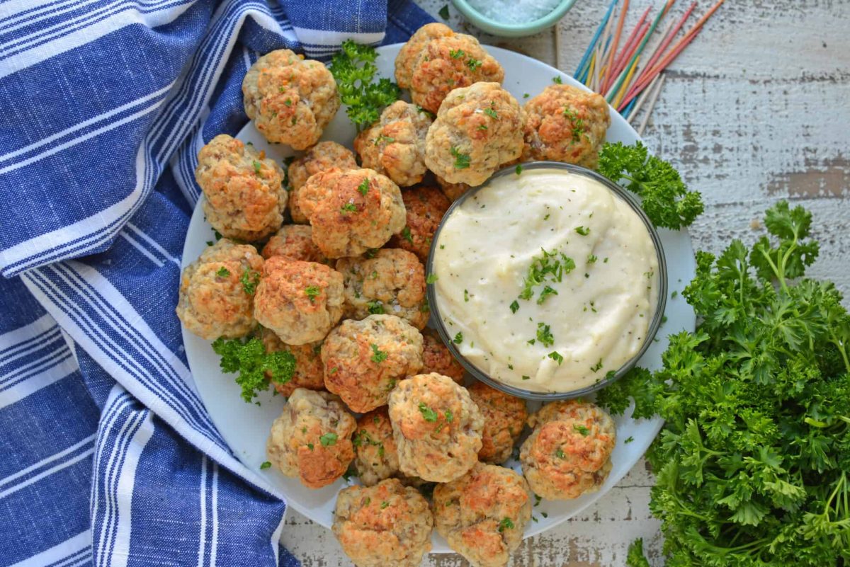 Overhead shot of cooked easy sausage balls on a white serving platter with dipping sauce 