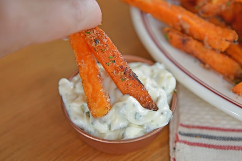 Sweet potato fries dipping into herb aioli 