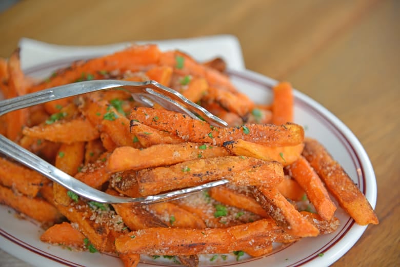 Sweet potato fries being served with large tongs