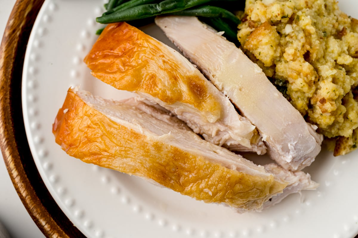 Sliced butter cheesecloth soaked turkey on a plate with stuffing