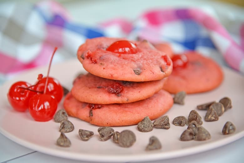 Stack of cherry chocolate chip cookies with maraschino cherries and chocolate chips