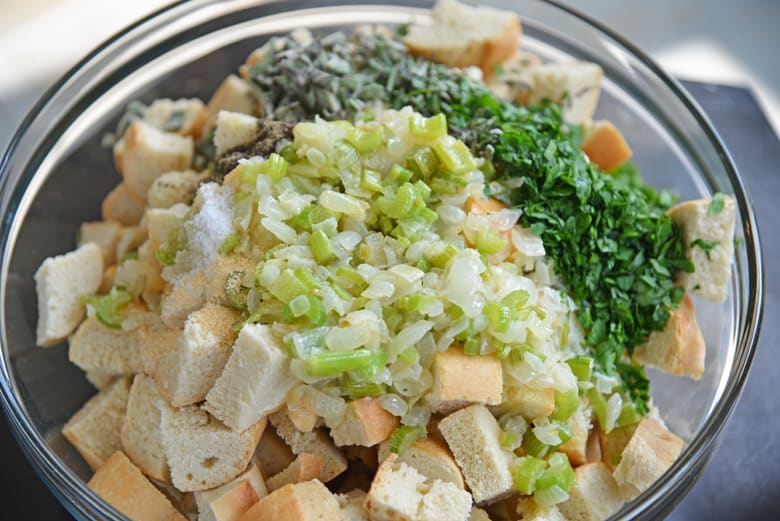 Wet and dry ingredients for herb stuffing in a large mixing bowl