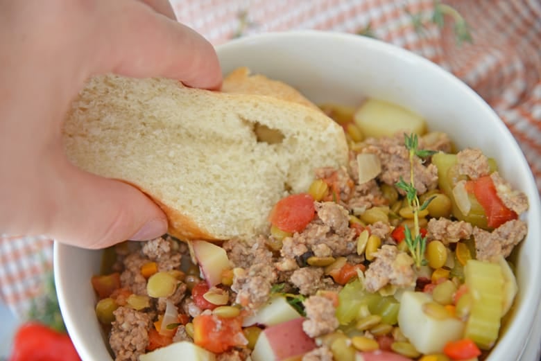 Crusty white bread dipping into lamb stew