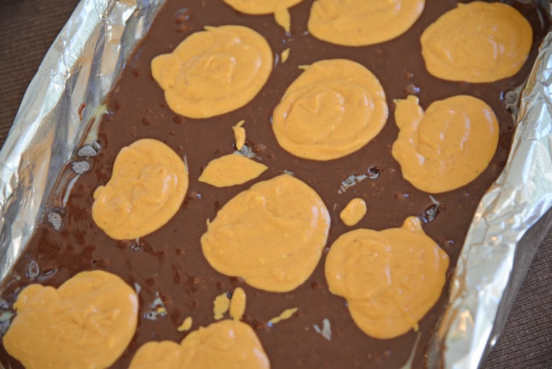 Spoonfuls of pumpkin cheesecake on brownie batter 