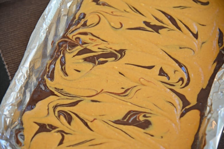 Side angle of pumpkin cheesecake brownies in a pan 