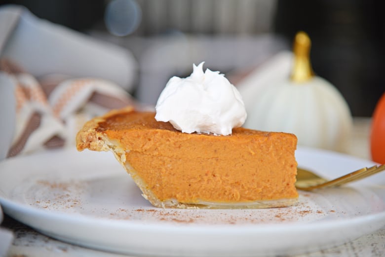 Side angle of pumpkin pie with whipped cream dollop 