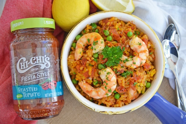 Bottle of salsa next to a bowl of shrimp paella 