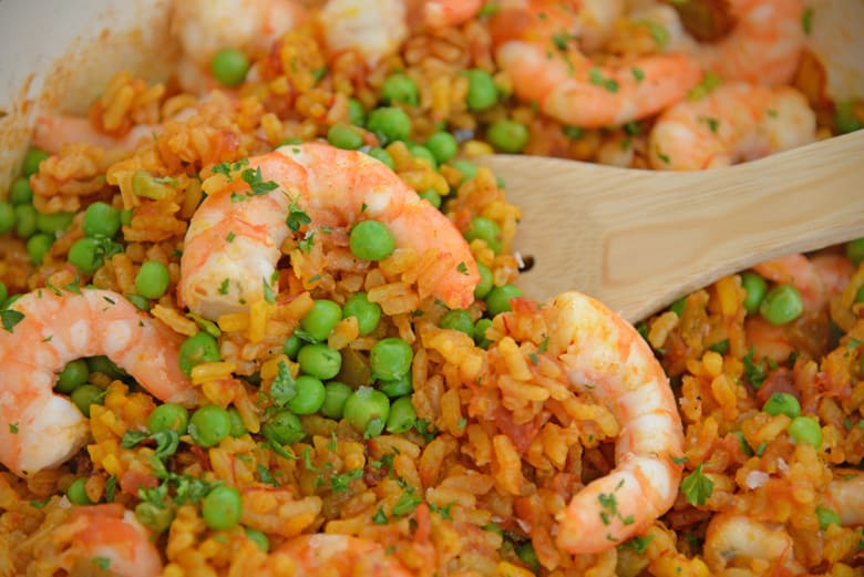 Wooden spoon with shrimp paella and peas 