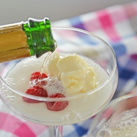 pouring champagne into a glass with ice cream and raspberries