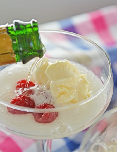 pouring champagne into a glass with ice cream and raspberries