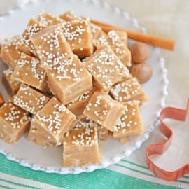 Gingerbread fudge on a white plate with a cookies cutter and cinnamon sticks