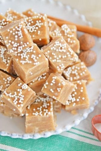 Gingerbread fudge on a white plate with a cookies cutter and cinnamon sticks