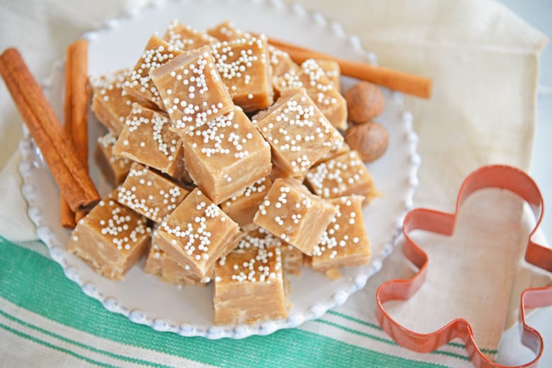 Gingerbread fudge on a white plate with a cookies cutter and cinnamon sticks