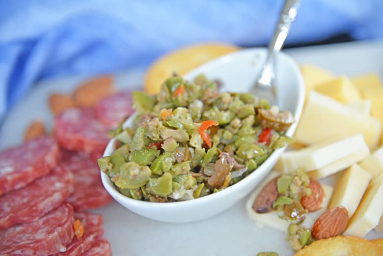 Spoon on a white bowl of olive tapenade 