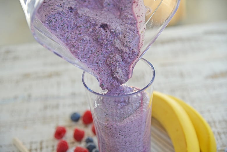 Purple smoothie pouring into a glass 