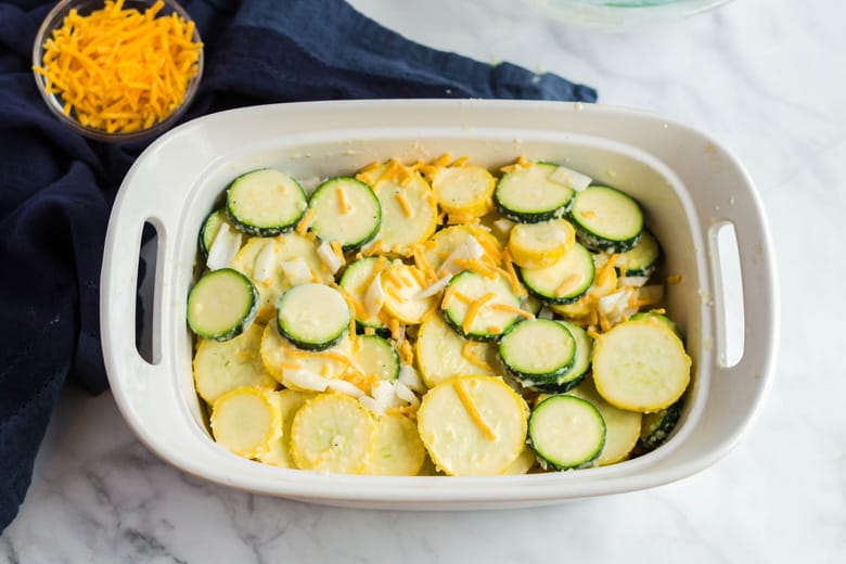 Layering yellow and green squash with cheese 