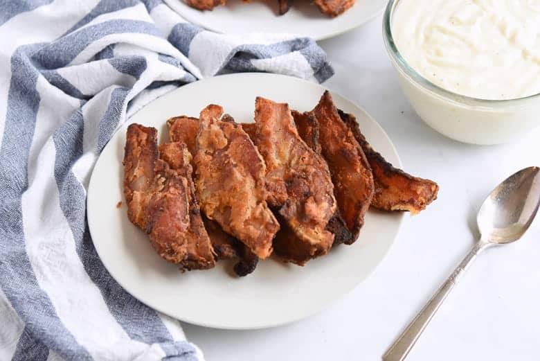 Chicken fried bacon on a white serving plate 