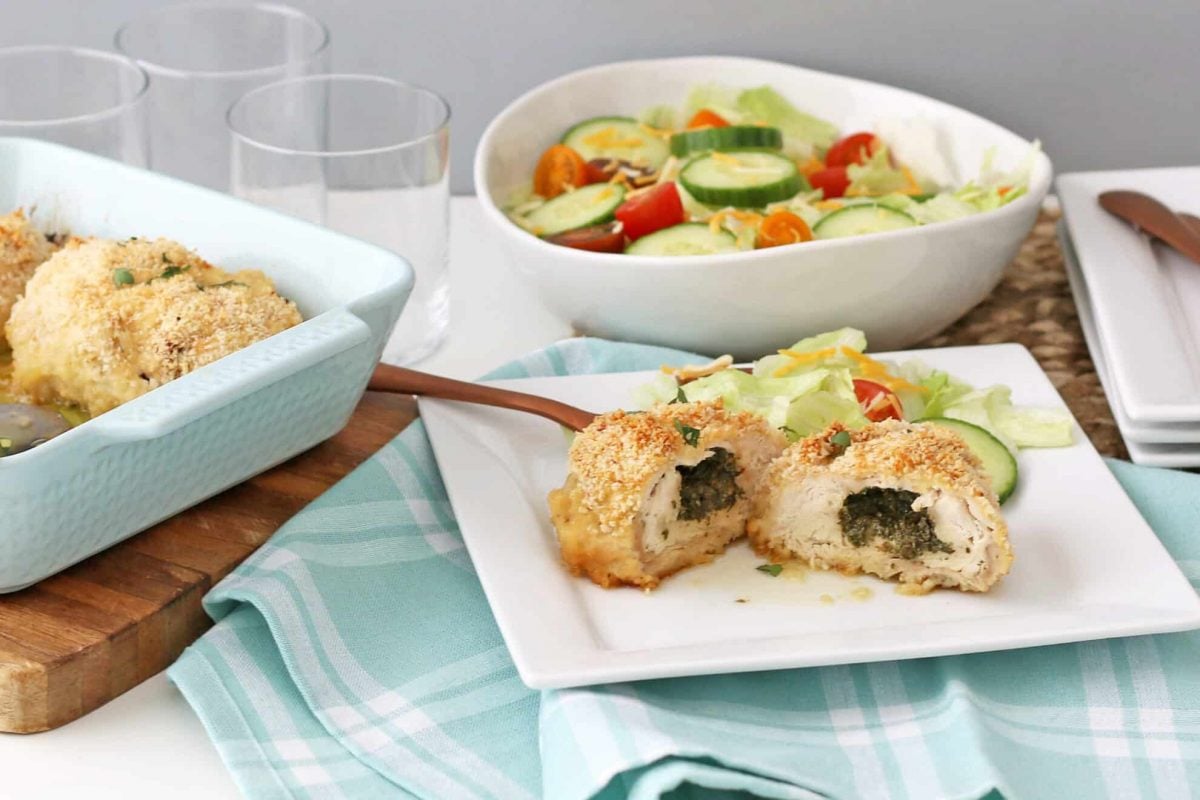 Table with a plate of chicken kiev and green salad 