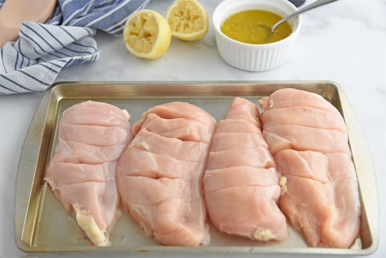 Raw chicken breasts on a cookie sheet 