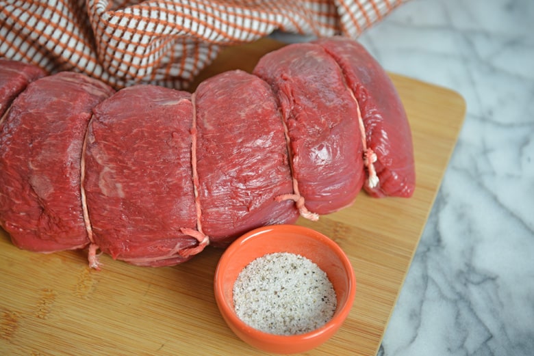 Tied beef tenderloin with salt and pepper seasoning on the side 